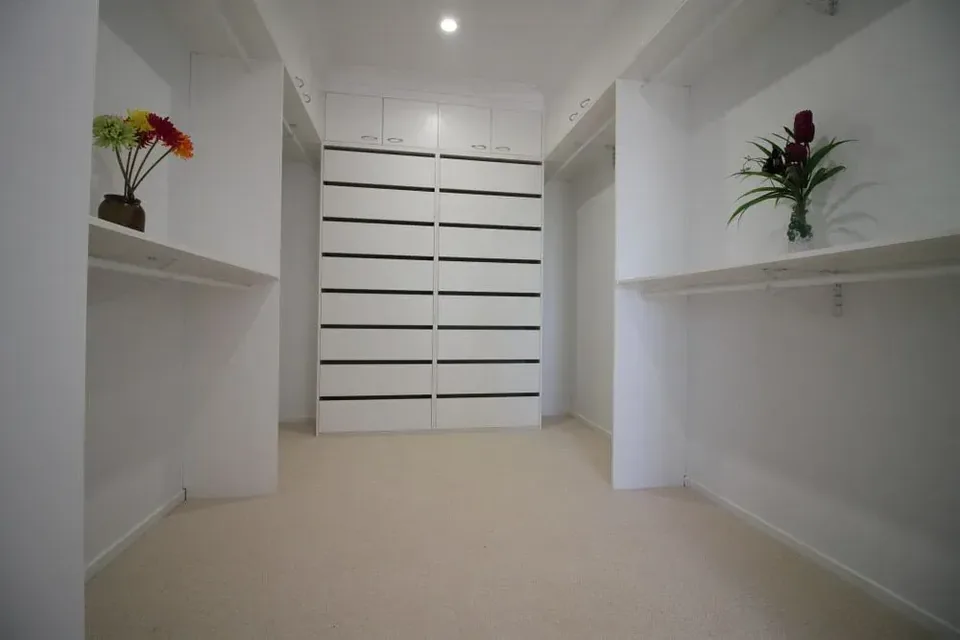 Walk-in wardrobe with white shelving, drawers and hanging rails