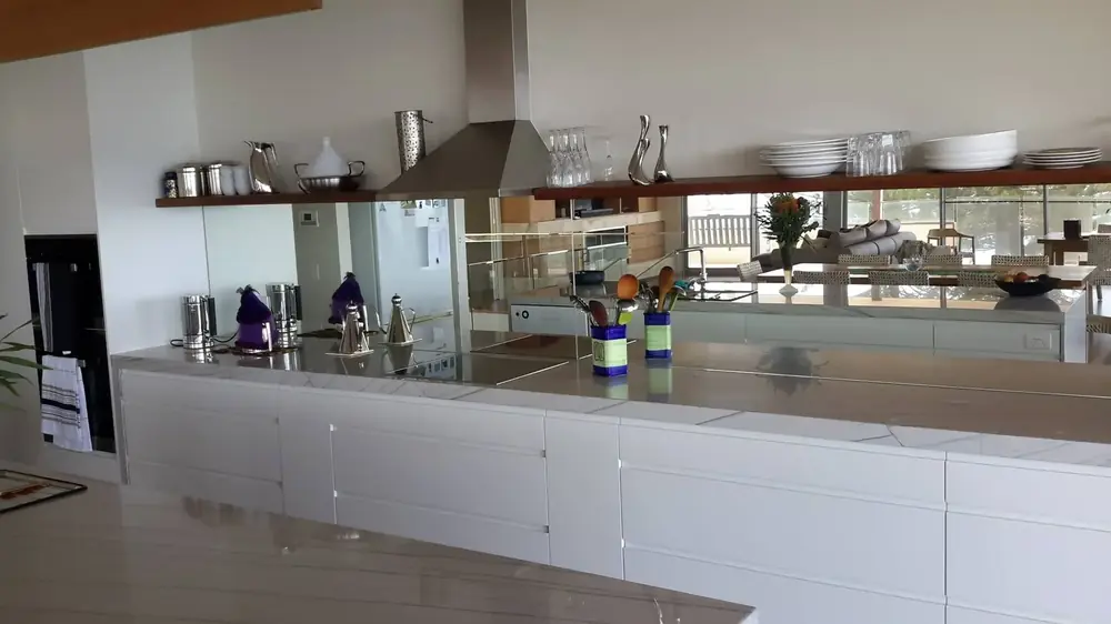 White kitchen with long benchtop, mirrored splashback and timber trim