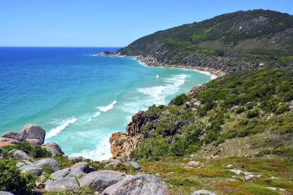 Rocky coastal headland above a long blue beach
