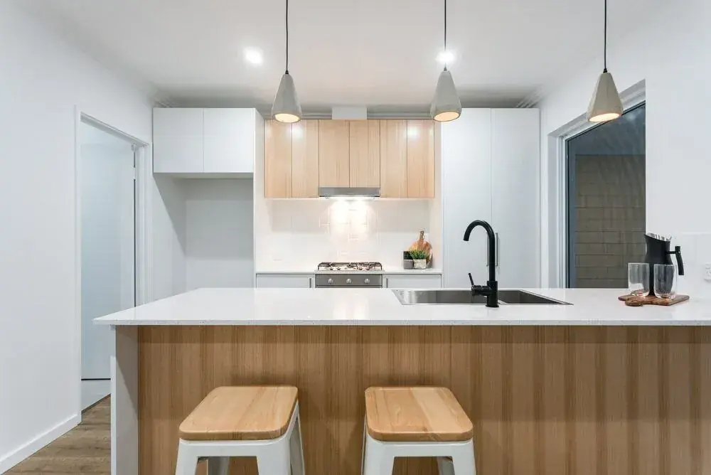 Custom kitchen with timber-front island, white cabinetry and pendant lights
