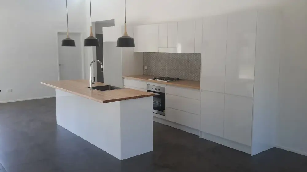 White kitchen with timber island benchtop and three pendant lights