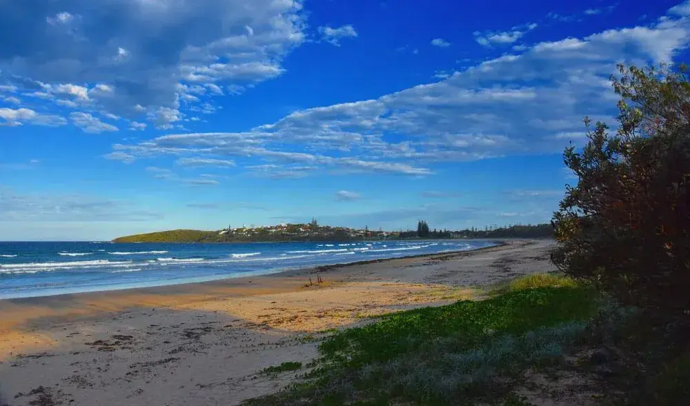 Sandy beach, rocky shoreline and blue ocean beneath a clear sky
